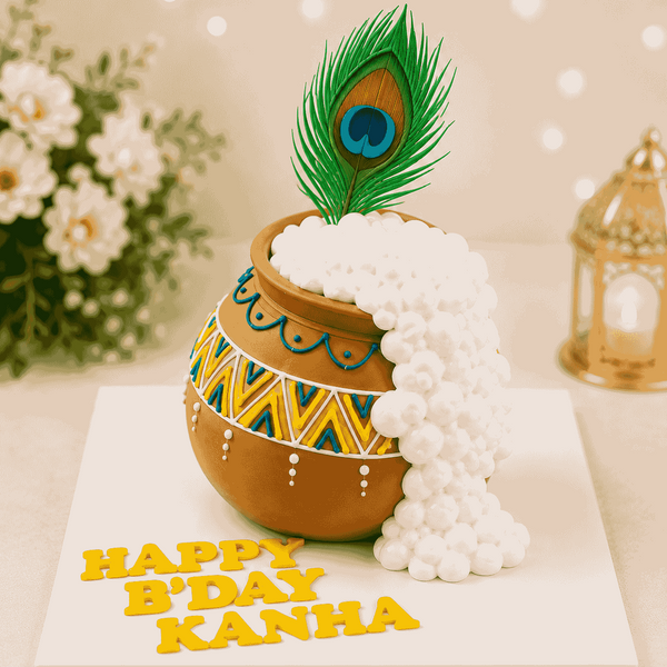 A 3D sculpted brown terracotta butter pot cake painted with blue and yellow motifs, with white makhan overflowing down the side, topped with a peacock feather.