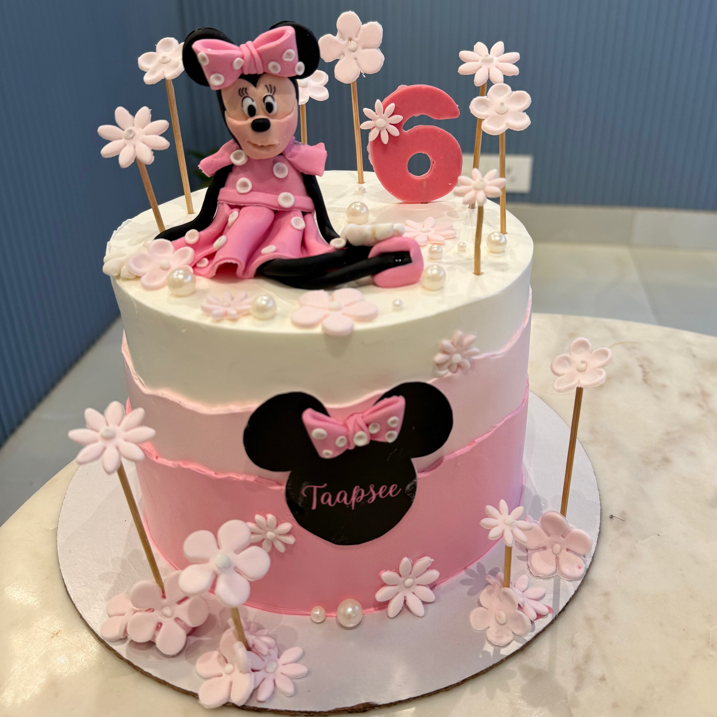 A 1.5kg Belgstrew Minnie Mouse cake with a pink polka-dot bow and a personalized gold name tag.