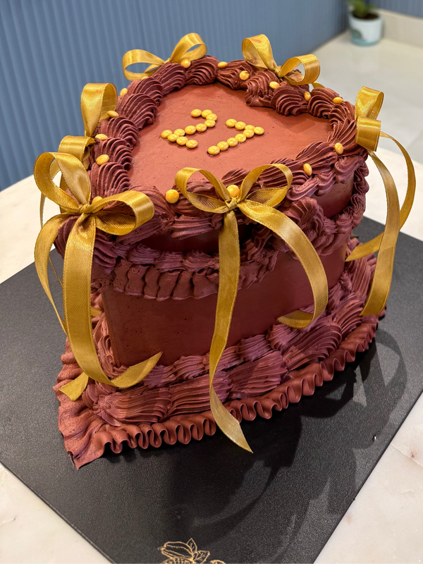 A 2kg Belgstrew Heart-Shaped Chocolate Cake with golden ribbon detailing and rich hazelnut praline layers.