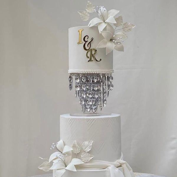 Decorative wedding cake with 'I & E' initials and crystal accents on a white background
