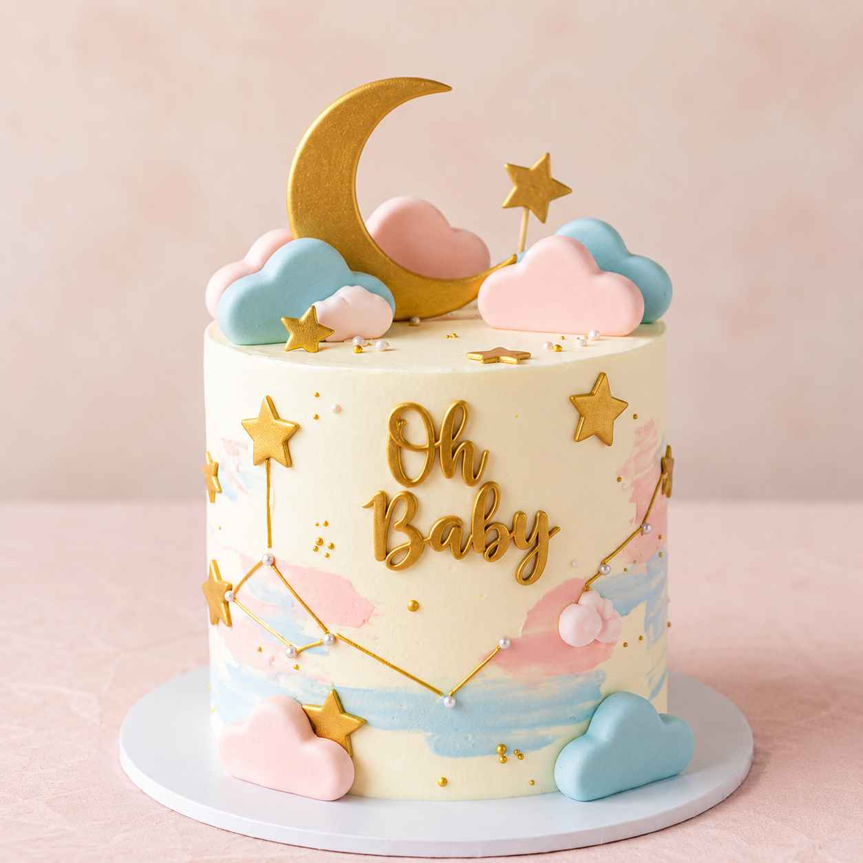 A tall ivory baby shower cake with pink and blue paint strokes, decorated with gold constellation lines, 3D pastel clouds, a large gold crescent moon, and gold stars.