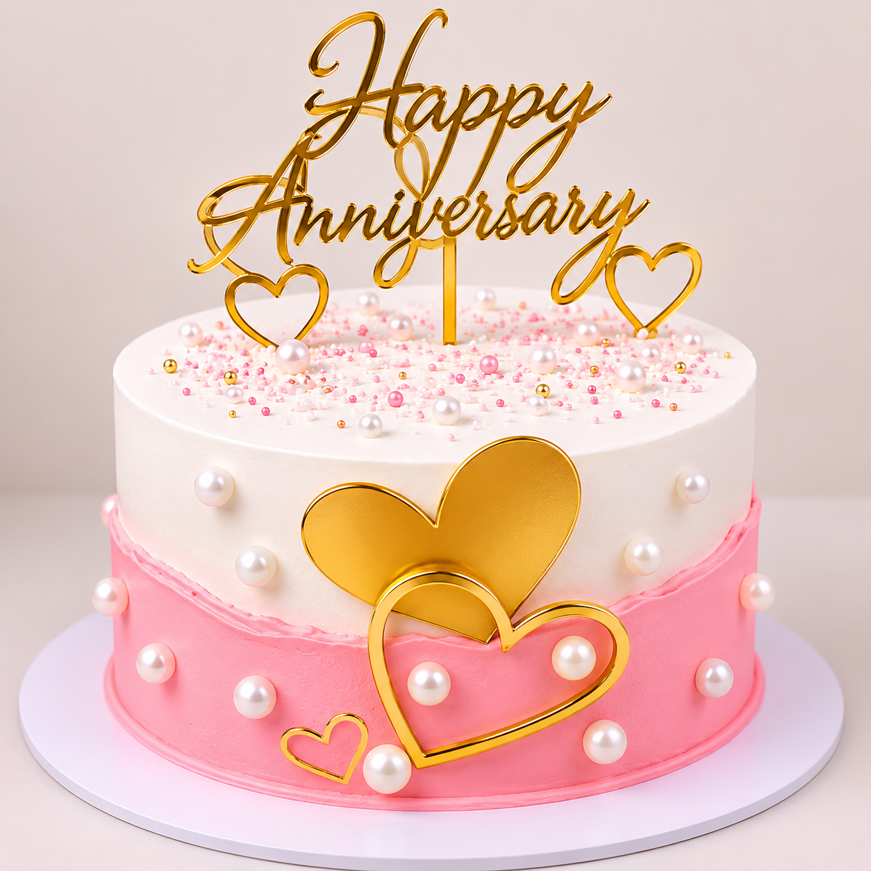 A white and pink anniversary cake designed with a pink fault line bottom half, decorated with large white edible pearls, pink sprinkles, and interlocking gold mirror hearts.