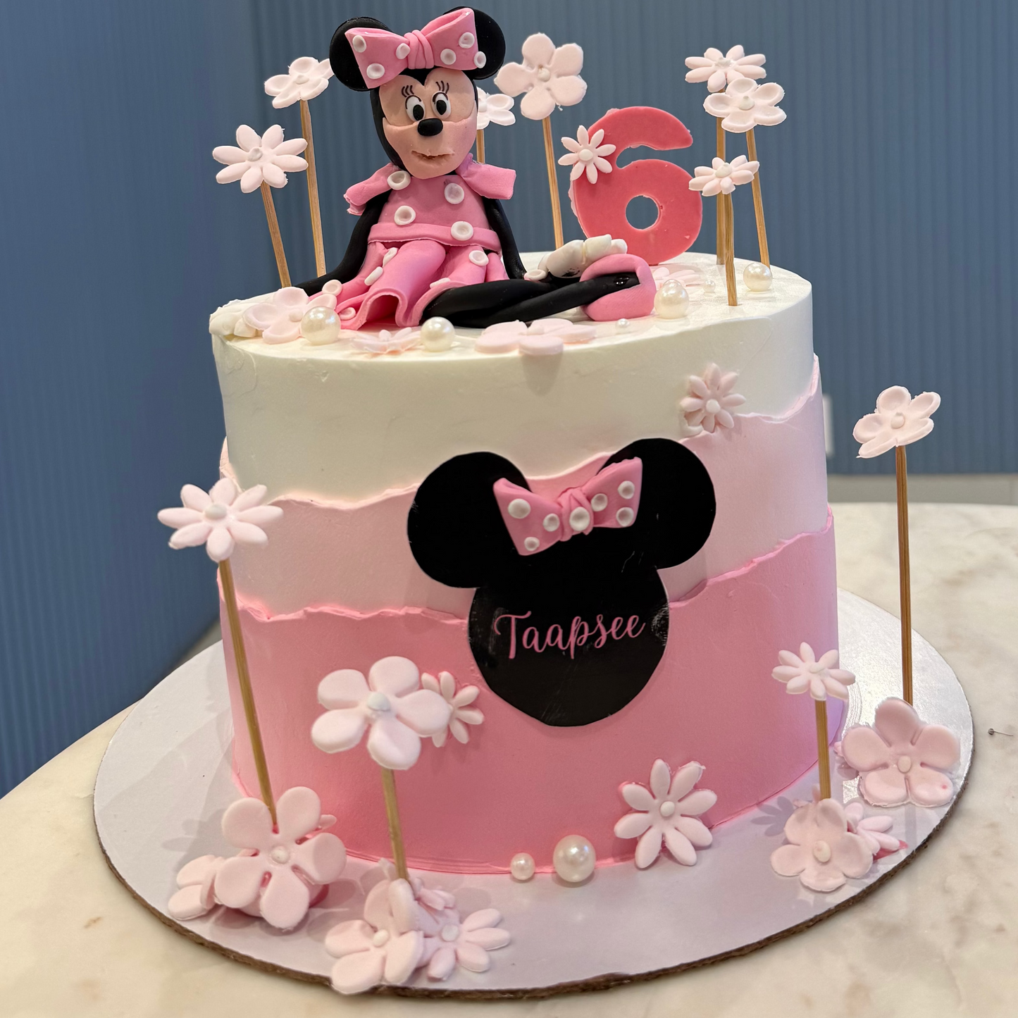 A 1.5kg Belgstrew Minnie Mouse cake with a pink polka-dot bow and a personalized gold name tag.