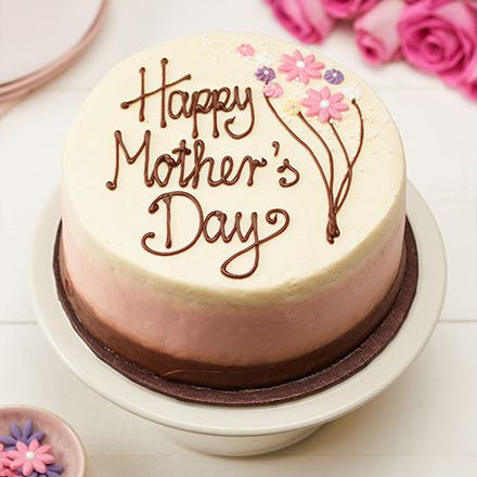 A 1kg ombré cake transitioning from brown to pink and white, decorated with "Happy Mother's Day" script and piped pink flowers.