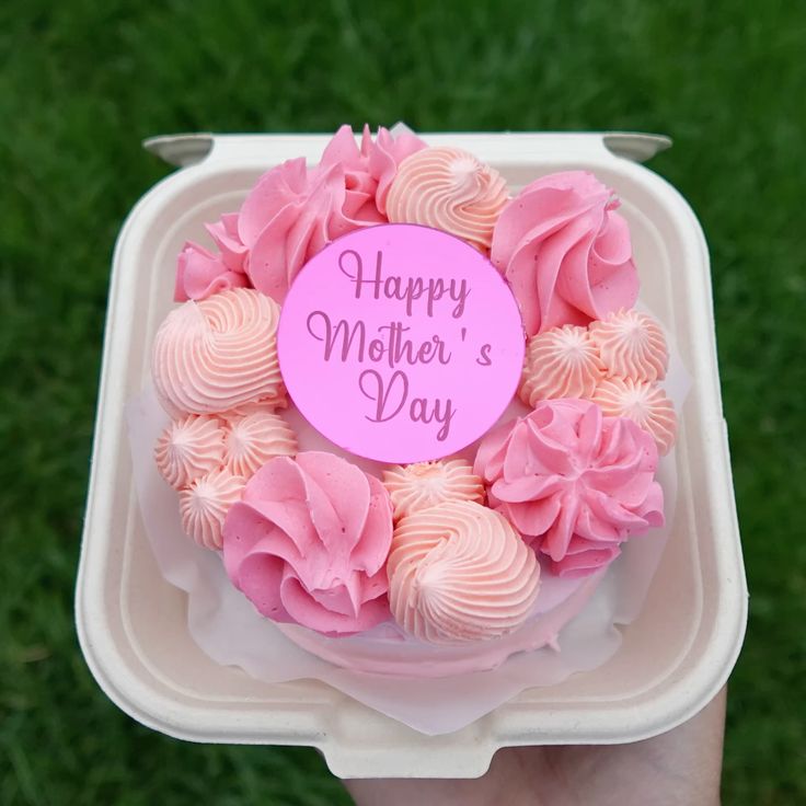 A bento cake with a dense wreath of pink and peach piped frosting swirls and a pink Happy Mother's Day topper.