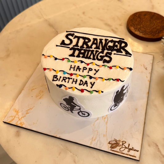 A bespoke Belgstrew Stranger Things cake featuring an edible Christmas light alphabet wall and retro 80s elements.