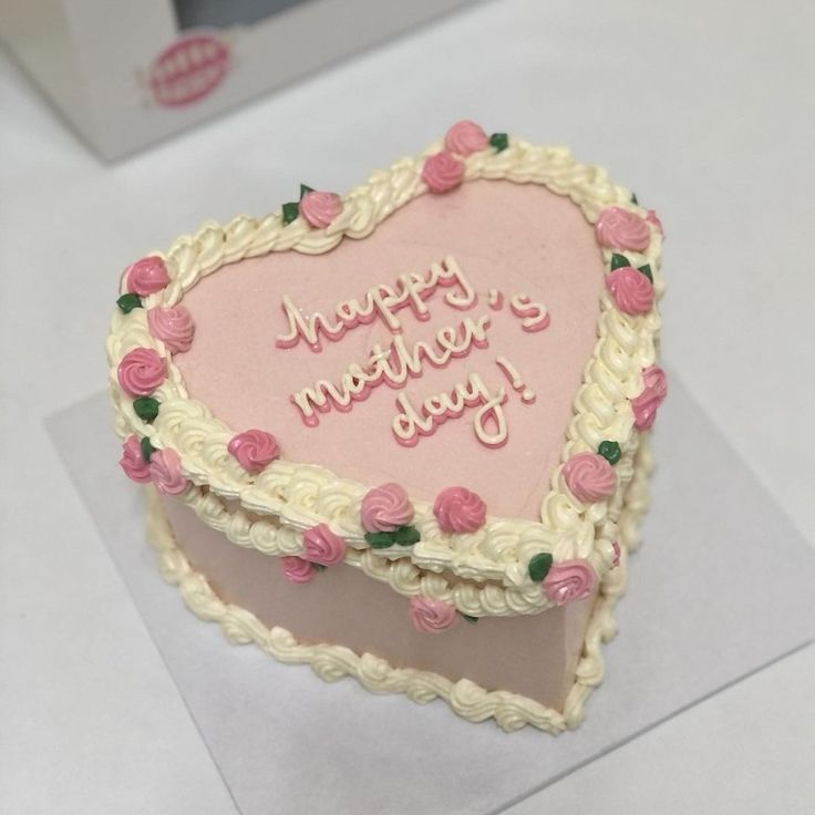 A dusty pink heart-shaped cake with ivory vintage shell piping and small pink piped roses for Mother's Day.