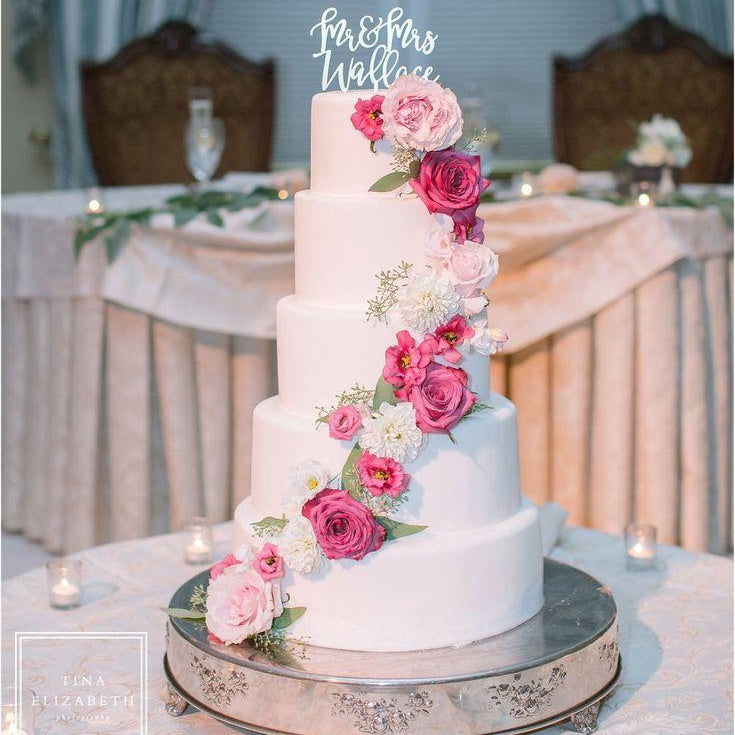 White wedding cake with pink and white flowers on a table with a blurred background