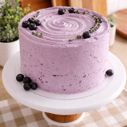 A slice of Belgstrew Vanilla Blueberry Cake showing the purple fruit filling between layers of white vanilla sponge and cream.