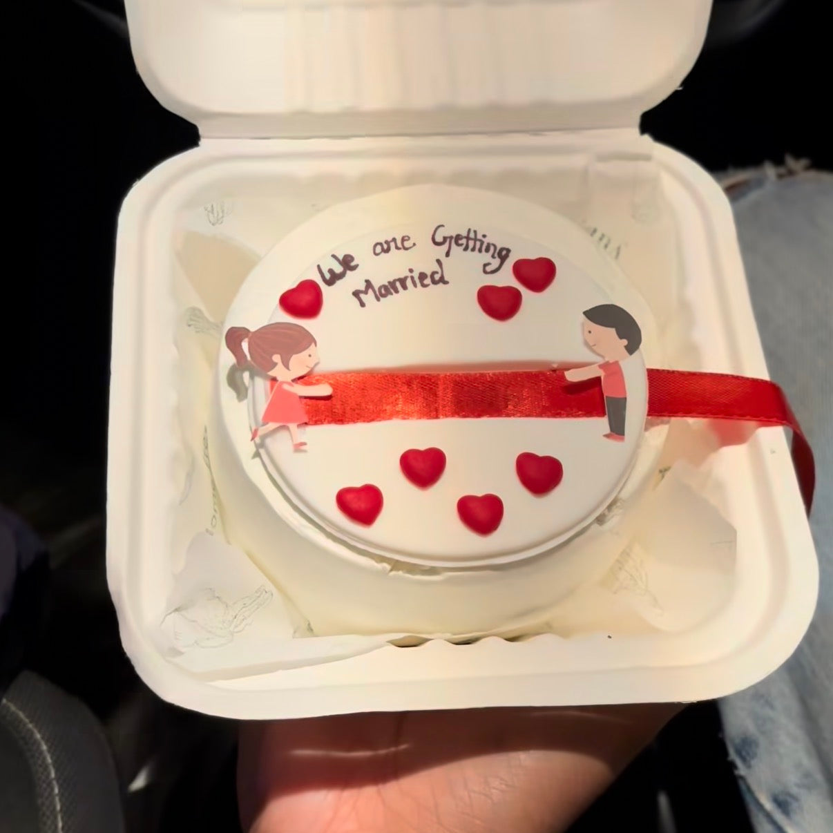 A Belgstrew 300g eggless ribbon pull bento cake with a "We Are Getting Married" surprise message reveal.