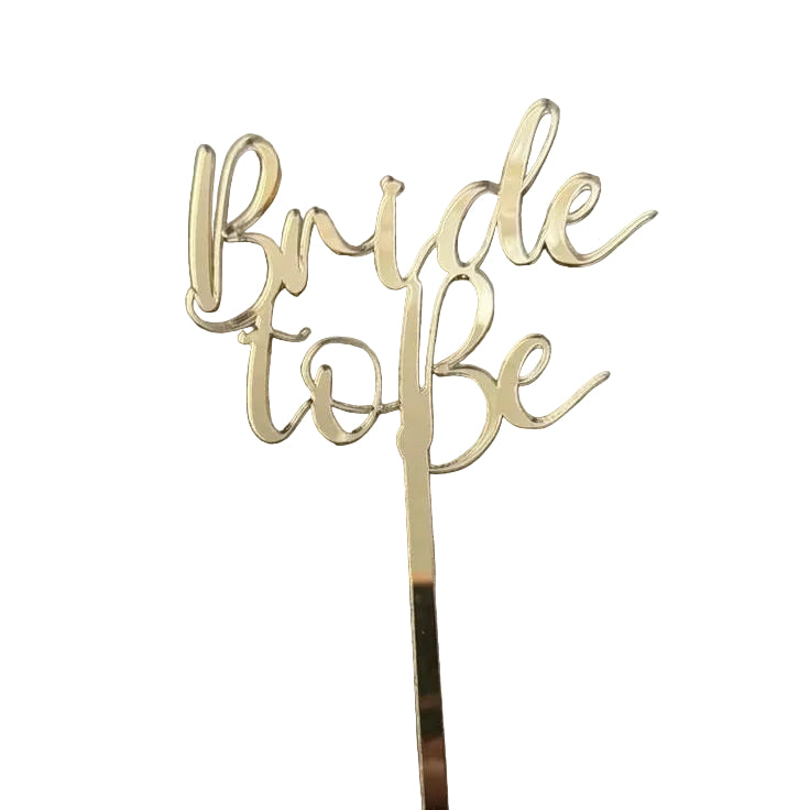 Gold 'Bride to Be' cake topper on a White surface