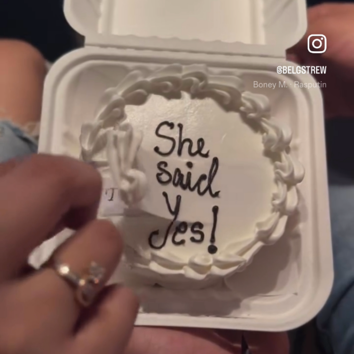 A Belgstrew eggless bento cake where the top white frosting layer is being peeled back to reveal a hidden "To someone else" message in white cursive.