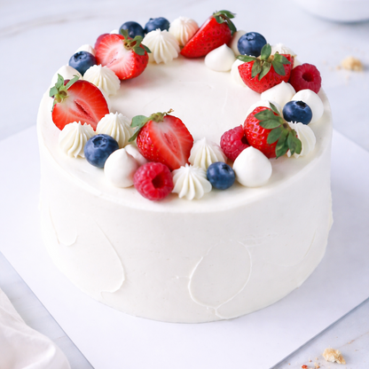 Top view of a Belgstrew Fresh Fruit Cake decorated with colorful slices of kiwi, grapes, and seasonal berries.