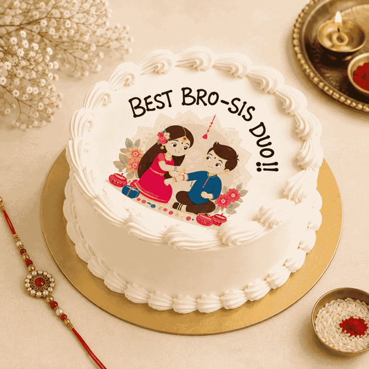 A round white frosted festive cake with piped shell borders and an edible top illustration of a sister tying a rakhi on her brother with text reading Best Bro-Sis Duo.
