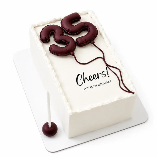 A minimalist white rectangular slab birthday cake decorated with 3D brown piped milestone numbers made to look like balloons, featuring clean black typography reading Cheers! It's your birthday as seen in image.